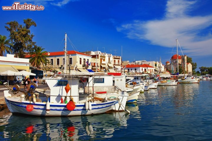 Immagine La marina e le barche dei pescatori  sul molo del porto di Egina (Aegina), l'isola del Golfo Saronico della Grecia. Sullo sfondo la bella chiesa di Agios Nikolaos Thalassinos - © leoks / Shutterstock.com