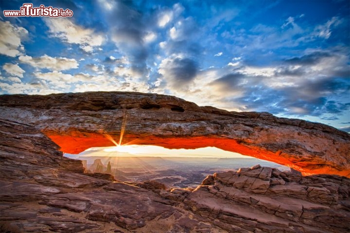 Immagine Mesa Arch è una delle meraviglie del Canyonlands National Park dello Utah, USA, situato nella zona del parco conosciuta come Island in the Sky. Nel tempo gli agenti atmosferici hanno corroso e modellato la roccia dando vita a capolavori come questo, simile a una scultura che incornicia la veduta sul canyon. Il Mesa Arch è facilmente raggiungibile a piedi grazie a un percorso ad anello di meno di un chilometro - © Erik Harrison / Shutterstock.com