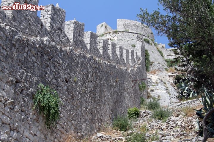 Immagine Mura e Torre a Hvar in Croazia. L'isola di Lesina, detta anche "la Lunga" è uno dei luoghi più densi di storia della Dalmazia e dell'intera Croazia. La Città di Hvar possiede un centro monumentale con una cinta muraria ancora perfettamente conservata, e fortificazioni sia veneziane che costruite durante il periodo napoleonico - © Valery Shanin / Shutterstock.com