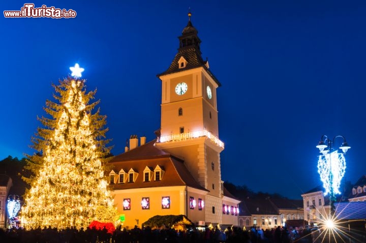 Immagine Natale a Brasov, Piazza Sfatului - Una bella immagine notturna ritrae i festeggiamenti celebrati in occasione del Natale nella città di Brasov. Piazza Sfatului, abbellita da un gigantesco albero natalizio e dalle tradizionali luminarie, diventa il luogo d'incontro di abitanti e turisti giunti sino a qui per festeggiare il Natale © Emi Cristea / Shutterstock.com