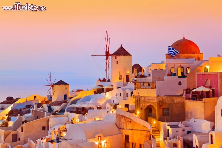 Immagine Oia a Santorini: l'isola di Thira al tramonto è uno dei luoghi più suggestivi delle Cicladi, anche per la sua posizine isolata e rialzata sull'Egeo. Siamo in Grecia e i mulini a vento indicano una discreta ventosità dell'isola - © Tatiana Popova / Shutterstock.com