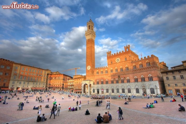 Immagine Il Palazzo Comunale di Siena affiancato dalla Torre del Mangia, in Piazza del Campo. Venne fatto costruire dal Governo dei Nove della Repubblica di Siena tra il 1297 e il 1310, e all'interno la sontuosa decorazione cominciò ancor prima che l'architettura fosse completa: ancora oggi affreschi, pitture e sculture qui custodite rappresentano una testimonianza preziosa dell'arte medievale e della cultura senese - © Mihai-Bogdan Lazar / Shutterstock.com