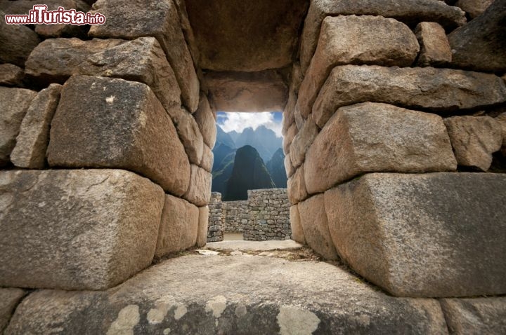 Immagine Palazzo di pietra a Machu Picchu, Perù - Un muro lungo circa 400 metri divide la città di Machu Picchu dalla zona agricola. All'interno si trovano edifici religiosi, abitazioni, torri di avvistamento e altre costruzioni realizzate con blocchi in pietra perfettamente incastonati l'uno sull'altro. I massi sono tutti di granito color biancoazzurro che deriva da cave situate nei pressi del complesso incaico, lavorati all'epoca degli inca con strumenti in bronzo e resi lisci dall'abrasione con la sabbia - © Jerome Stubbs / Shutterstock.com