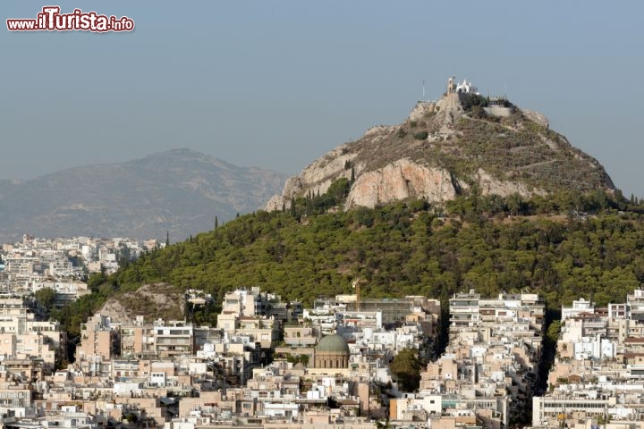 Immagine Il Monte Licabetto (272,7 metri), il punto più alto di Atene visto dal Partenone e la città circostant. Il centro di Atene ospita una popolazione di circa 800.000 abitanti, ma la sua crescita ha inglobato i villaggi vicini in una grande conubazione di quasi 4 milioni di persone. La distesa di palazzi e case bianche, viste dall'Acropoli, è impressionante. Il quartiere più turistico si trova appena sotto le rocce dell'Acropoli e prende il nome di Plaka - © Natalia Bratslavsky / Shutterstock.com