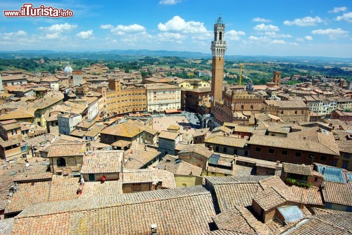 Immagine Veduta aerea del centro storico di Siena, nel cuore della Toscana. Il centro medievale, ricchissimo di testimonianze storiche e caratterizzato da un'eccezionale unità architettonica, è stato dichiarato Patrimonio dell'Umanità dall'UNESCO nel 1995. Da lontano si riconosce la Torre del Mangia, che affianca il Palazzo Comunale, e la disposizione a ventaglio di alcuni palazzi intorno a Piazza del Campo - © Igor Plotnikov / Shutterstock.com