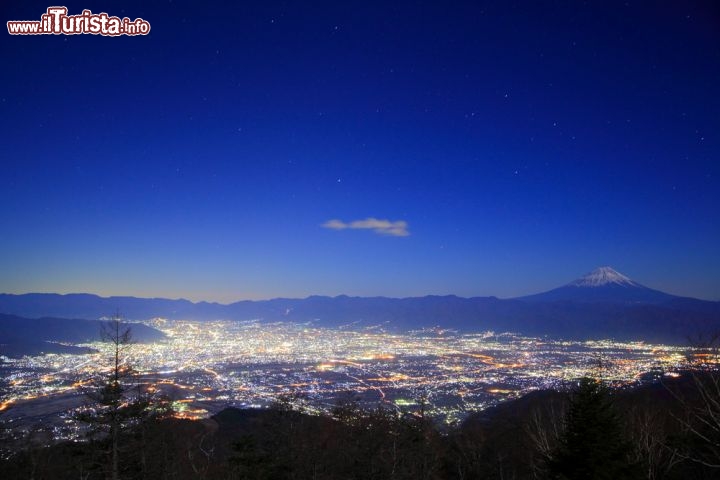 Immagine Il magnifico panorama notturno con monte Fuji. In basso le luci delle città della prefettura di Yamanashi, che si trova a nord della montagna sacra del Giappone - © Norikazu / Shutterstock.com