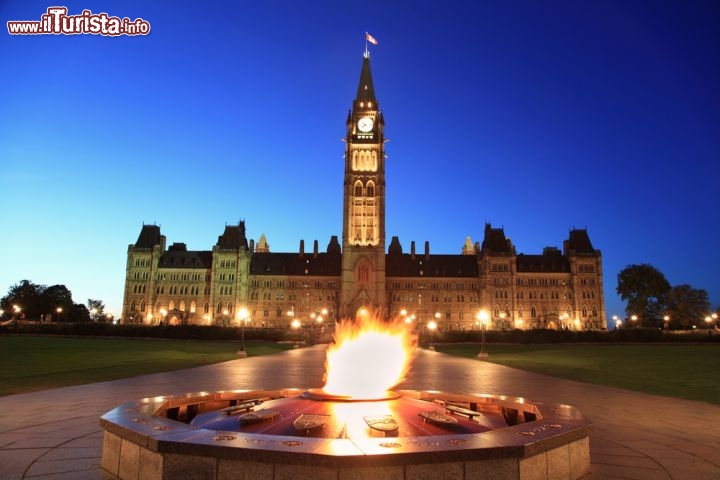 Immagine Ottawa, Ontario: il Parlamento del Canada by night, con la centrale Torre della Pace illuminata. Nell'immagine il corpo principale degli edifici governativi, il cosiddetto Centre Block, incorniciato da ampi prati e da una bella passeggiata panoramica sul fiume Ottawa  - © Vlad G / Shutterstock.com
