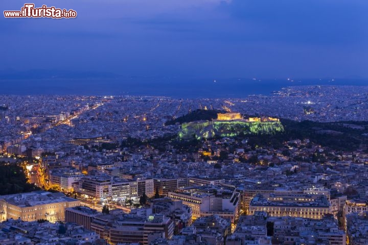 Immagine Il Partenone e l'Acropoli alla sera dominano in modo drammatico il centro di Atene (Grecia). Tutti i turisti volgono lo sguardo a questo luogo rialzato, denso di storia, e vero simbolo di democrazia nel mondo. C'è chi visita la capitale della Grecia limitandosi alle rovine della città alta, l'Acropoli, ma, seppur limitata, questa scelta è d'obbligo dato lo straordinario valore archeologico e simbolico del Partenone. Da qui poi si gode di un panorama straordinario su tutta Atene - © Anastasios71 / Shutterstock.com