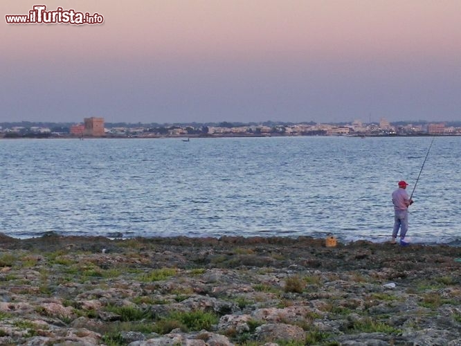 Immagine Pescatore sullo Jonio in Puglia,  sullo sfondo Porto Cesareo al tramonto con visibile Torre Chianca