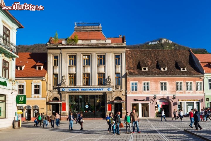 Immagine Centro storico di Brasov, Romania - Fondata nel XIII secolo da un gruppo di cavalieri teutonici su incarico del re d'Ungheria, Brasov vanta un suggestivo centro storico che ha sostanzialmente mantenuto intatto il suo aspetto così come buona parte della cinta muraria che lo delimita. In quest'immagine Piazza Sfatului (Piazza del Consiglio) su cui si affacciano palazzi e attività commerciali della città rumena © Emi Cristea / Shutterstock.com