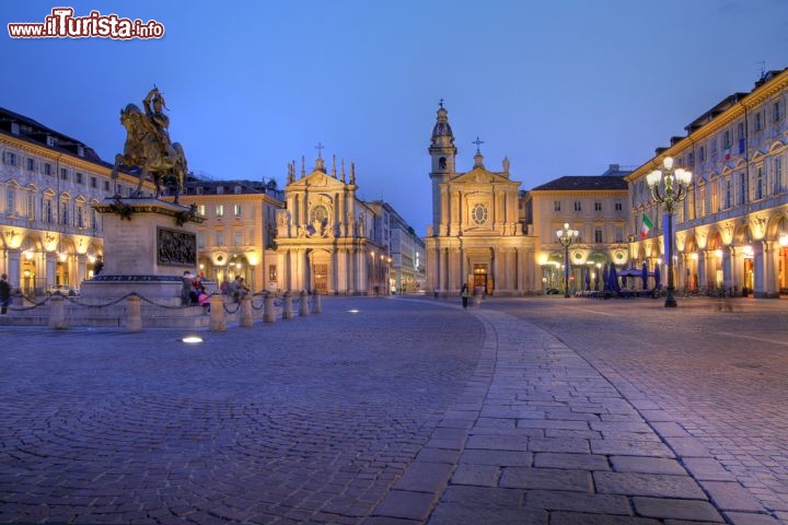 Immagine Piazza San Carlo è un po' il "salotto" di Torino ed è particolarmente scenografica al tramonto, quando iniziano ad accendersi i lampioni della sera. Di forma rettangolare, unita a Piazza Castello mediante Via Roma, oggi si presenta così come la progettò Carlo di Castellamonte nel 1600, più qualche aggiunta settecentesca di Benedetto Alfieri. Ospita la statua equestre di Emanuele Filiberto e vi si affacciano il Solaro del Borgo e le chiese gemelle di età barocca - © Mihai-Bogdan Lazar / Shutterstock.com