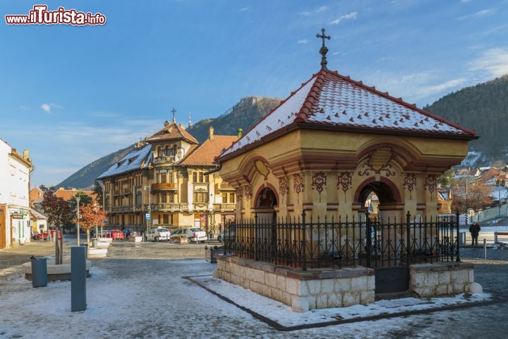 Immagine Inverno in Piazza Unirii, Brasov - I suoi suggestivi edifici otto novecenteschi sembrano quasi contrastare la vegetazione lussureggiante di boschi e foreste che inizia da li a poco. Conosciuta anche come piazza dell'unificazione, Piata Unirii - qui ritratta in inverno sotto una soffice coltre di neve - è una delle piazze simbolo di questa città della Romania inconrniciata dai Carpazi meridionali  © Photosebia / Shutterstock.com