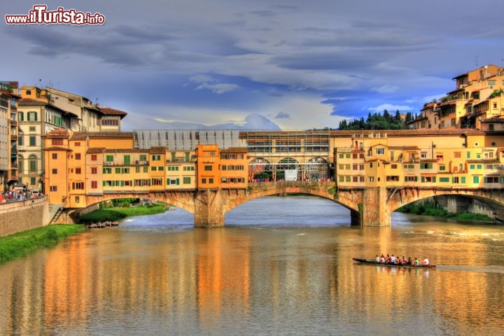 Immagine Ponte Vecchio a Firenze. E' uno dei simboli della città Toscana e che l'ha resa famosa nel mondo. Il fiume Arno veine attraversato con 3 grandi arcate. La prima versione in pietra risale al 1170, ma durante la piena del 1333 il ponte venne completamente distrutto. La versione che ammiriamo oggi risale al 1345. E' famoso per le sue botteghe, oggi meta privilegiata di shopping di alto livello, con moltissimi orafi, ma le prime furono quelle dei beccai, e cioè dei macellai che erano stati posizionati sopra al fiume per ragioni igieniche. Sopra le botteghe si trova il "Corridoio del Vasari", il percorso di collegamento che unisce Palazzo Vecchio a Palazzo Pitti, passando sopra la Galleria degli Uffizi e per l'appunto sul Ponte vecchio, che qui vediamo ripreso al tramonto - © Francisco Caravana / Shutterstock.com