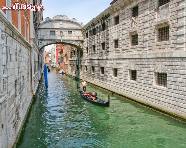 Immagine Ponte dei sospiri a Venezia, con gondola di passaggio. Questo ponte coperto collega il Palazzo Ducale con le prigioni, ed è per questo motivo vhe è stato chiamato dei sospiri, cioè quelli dei condannati che passano qui per il loro ultimo viaggio da uomini liberi. E' un ponte barocco, costruito da Antonio Contin che lo completà nel 1603. In teoria oggi gli unici sospiri che si possono cogliere sono quegli degli innamorati che si scambiano affettuosi baci mentre passano al di sotto in gondola - © Pavel Ilyukhin / Shutterstock.com