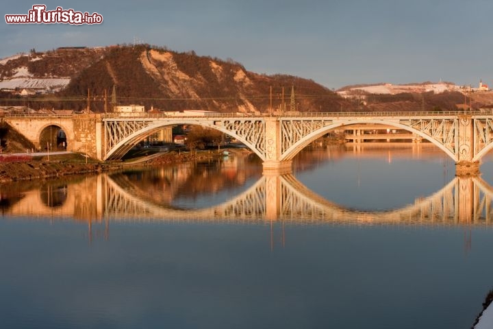 Immagine Panorama sul ponte del fiume Drava, Maribor - Tre archi d'acciaio collegano per circa 270 metri le due sponde della città slovena. Considerata una dei simboli di Maribor, questa struttura viene ricordata con diversi nomi - ponte vecchio, ponte di Stato, ponte Drava... - a sottolineare la grande importanza che riviste per gli abitanti della città. Danneggiato nel corso della Seconda Guerra Mondiale, il ponte venne ristrutturato negli anni successivi per poi tornare ad essere transitabile in tutta sicurezza. Gli ultimi interventi di ripristino furono eseguiti nel 1990 e nel 1998 © Istvan Csak / Shutterstock.com