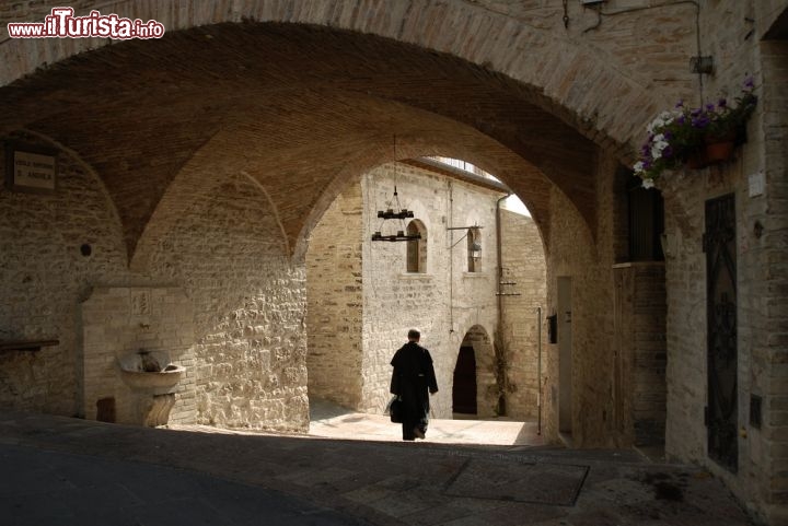 Immagine Un prete a passeggio nel borgo storico di Assisi in Umbria. Visitare la città dove nacque e visse il santo patrono d'Italia ha un importante significato storico e artistico oltre che religioso: la sua bellezza è da ricercarsi nell'atmosfera dei luoghi che la storia e la fede di San Francesco hanno reso unici nel mondo © shippee / Shutterstock.com