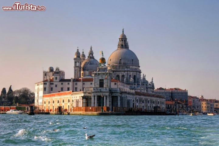 Immagine Santa Maria della Salute lungo il Canal Grande. La Basilica è un ex voto alla Madonna che salvò Venezia dalla peste a inizio '600. Venne consacrata nel 1687 e si trova presso la Punta della Dogana - ©. JuliaSha/ Shutterstock.com