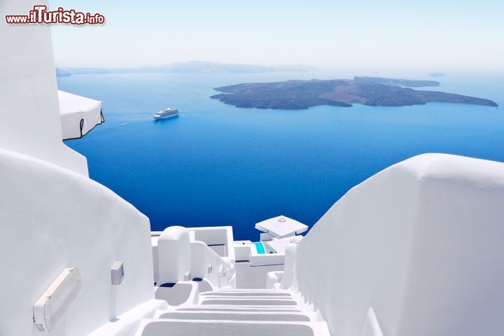 Immagine Una scala bianca di un villaggio di Santorini, con sullo sfondo i vulcani  Nea e Paleo Kameni, ed una nave da crociera - © freedombreeze / Shutterstock.com