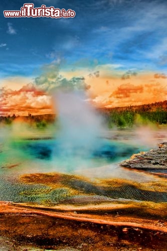 Immagine Una sorgente termale (Hot spring) nel Parco di Yellowstone, Wyoming (USA): in questa foto i colori dei fanghi e della sorgente si confondono con quelli del tramonto - © Shawn Zhang / Shutterstock.com