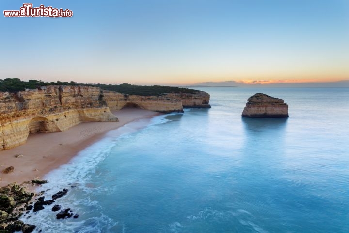 Immagine Calar del sole in una spiaggia di Albufeira - Coste frastagliate che si specchiano nelle acque dell'Oceano Atlantico contrastano le sfumtaure del bianco candido che caratterizzano le soffici spiagge dell'Algarve che, oltre a sole e mare, offre ai turisti una gastronomia ricca di pesce fresco pescato lungo il litorale © Sergio Stakhnyk / Shutterstock.com