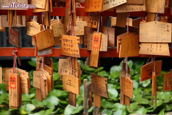 Immagine Tavolette delle preghiere a Kyoto, Giappone - Gli ema sono piccole tavole in legno in cui i fedeli della religione shintoista scrivono preghiere e desideri. Normalmente hanno forma pentagonale irregolare con una base di circa 20 cm. All'ingresso di questo tempio di Kyoto, credenti ma anche turisti provenienti da tutto il mondo lasciano i loro ema, termine che in giapponese siginifica immagine di cavallo perchè un tempo i cavalli reali venivano offerti ai luoghi di culto in cambio di salute e benedizione © Sergii Rudiuk / Shutterstock.com