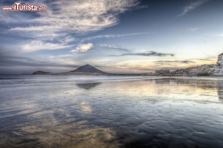 Immagine Tramonto a Playa El Médano (Tenerife, isole Canarie). Questa spiaggia si trova all'estremità meridionale dell'Isola di Tenerife, all'inizio della cosiddetta Costa del Silencio, che in clude anche le spiagge di playa de la Tejita, de los Abrigos e Playa Colmeranas. Questa spiaggia corona l'insenatura su cui si affaccia la cittadina di El Medano, chiusa ad occidente da profile di punta del Bocinegro e della montagna vulcanica Roja  - © Anibal Trejo / Shutterstock.com