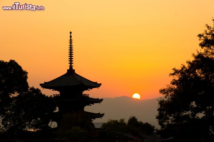 Immagine Tramonto a Kyoto, Giappone - Raggi di luce dalle mille sfumature giallo e arancio illuminano il tramonto che fa da sfondo a una caratteristica pagoda giapponese. Siamo a Kyoto, capoluogo dell'ominima prefettura, nel passato capitale del paese per più di un millennio, nota anche come città dai mille templi. Fa parte dei siti patrimonio dell'Unesco © kqlsm / Shutterstock.com