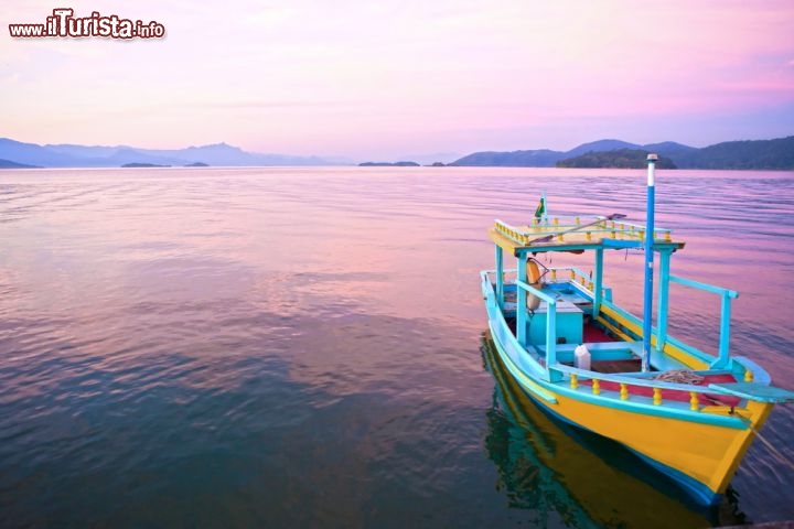 Immagine Un tramonto struggente nella baia di Paraty: una barca di un pescatore nella luce calda ed arrossata della sera in Brasile - © ostill / Shutterstock.com