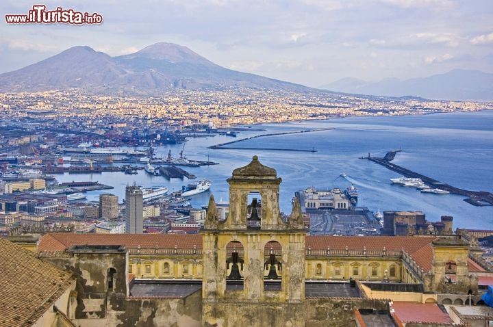 Immagine Il Vesuvio visto dai quartieri alti di Napoli. In primo piano l'Eremo di Camaldoli e in ombra il Porto di Napoli. Sullo sfondo si notano i profili del Vesuvio (a destra) e del monte Somma (a sinistra). Il monte Somma rappresenta il resto dell'edificio vulcanico che determinò la spaventosa eruzione del 79 d.C., quella che spazzò via le città romane di Pompei ed Ercolano. L'eremo di Camaldoli si trova nella parte ocest di Napoli, sull'omonia Collina. Fu eretto nel 1585 - © edella / Shutterstock.com