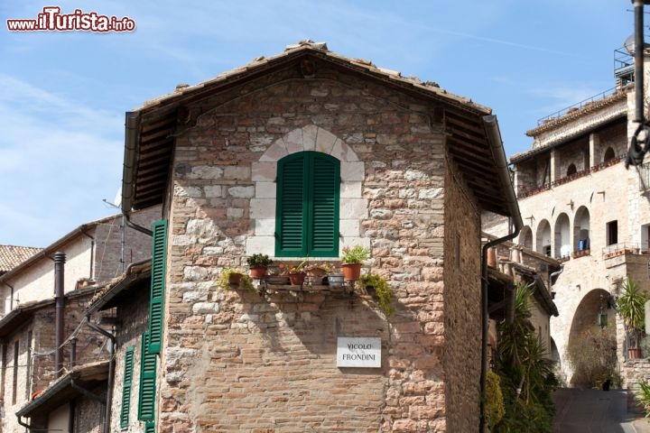 Immagine Un suggestivo scorcio panoramico su vicolo Frondini. Il centro storico di Assisi ospita un dedalo di vie e viuzze su cui affacciano antiche abitazioni in pietra impreziosite da scuri in legno e fiori colorati - © wjarek / Shutterstock.com