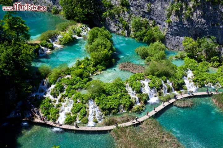 Immagine Vista aerea dei laghi Plitvice, Croazia - In una vallata incastonata fra montagne verdi e ricoperte di foreste fitte, 16 laghi di acqua smeraldo si susseguono fra loro in un tripudio di cascate, rapide e ruscelli. Di origine carsica, i laghi sono collegati da 92 cascate di varie dimensioni con alcuni salti che raggiungono i cento metri di altezza: la visita si svolge percorrendo dei camminamenti in legno che consentono di passeggiare a pelo d'acqua © Royalty Free Stock Photos / Shutterstock.com