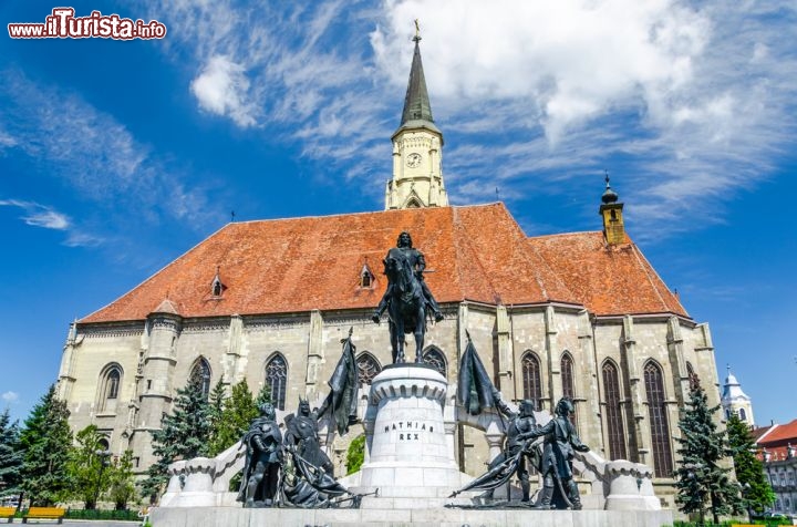 Immagine Chiesa di San Michele e statua di Re Mattia, Cluj Napoca - Vista laterale sulla chiesa di Saint Michael e sul monumento innalzato in onore di Mattia Corvino, detto anche il giusto. Appartenente ad una famiglia nobile e ricca, nel 1458 alla morte di re Ladislao V, Mattia venne eletto re d'Ungheria. La tradizione lo vuole essere stato un re saggio soprattutto per la sua abitudine, almeno a quanto è stato tramandato, di aggirarsi in incognito nel paese per parlare con il popolo e scoprire le truffe messe in atto dai vari potenti locali. A lato della chiesa di San Michele trobeggia una statua a lui dedicata © David Ionut / Shutterstock.com