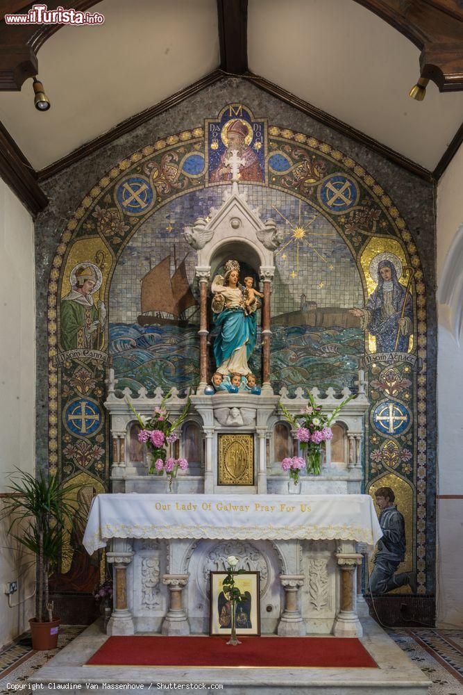 Immagine L'altare laterale con Maria e il bambino nella chiesa di Santa Maria a Galway, Irlanda. La scultura ha come sfondo un bellissimo mosaico con immagini di religiosi, una nave nell'oceano e la skyline della città - © Claudine Van Massenhove / Shutterstock.com