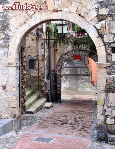 Immagine Un arco in pietra nel centro storico di Sanremo - il centro storico di Sanremo, chiamato "La Pigna" per le sue vie ammassate l'una all'altra che ricordano la forma di una pigna, è uno tra i più caratteristici borghi medievali dell'intera costa ligure. E' un susseguirsi di archi, cortiletti e fontane in un tripudio di architettura e dettagli gotici.  - © maudanros / Shutterstock.com