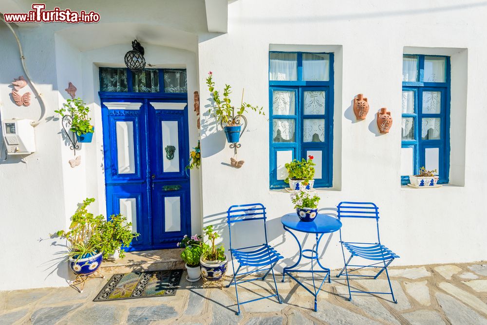 Immagine Architettura greca nel villaggio di Mandraki, Grecia, con finestre e porte blu e muri bianchi.