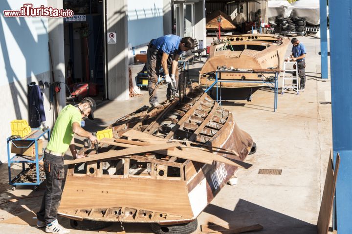 Immagine Artigiani al lavoro in un cantiere di Salò, Lombardia. Questo bel comune della provincia di Brescia si affaccia sull'omonimo golfo del lago di Garda ed è racchiuso a sud dai Colli Morenici e a nord dal Monte San Bartolomeo. In questa immagine, un gruppo di artigiani intenti alla costruzione di barche - © Alessio Moiola / Shutterstock.com