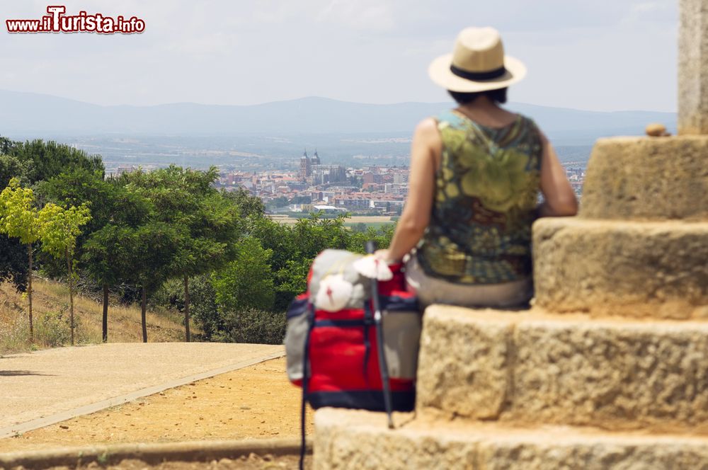 Immagine Astorga, Cammino di Santiago di Compostela: una pellegrina seduta su una croce di pietra osserva il panorama a Astorga (Spagna).