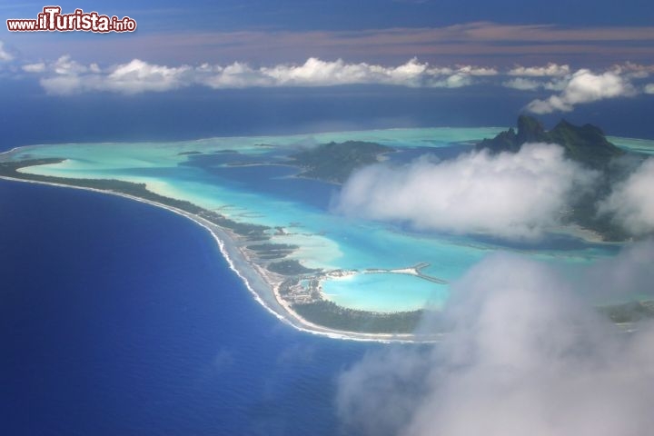 Immagine L'atollo di Bora Bora (Isole della Società, Polinesia Francese) visto dall'alto in una giornata di nuvole. La stagione delle piogge va da novembre a aprile: le temperature sono leggermente più alte rispetto al resto dell'anno e nell'arco della giornata il cielo muta più volte, si verificano temporali improvvisi o addirittura uragani nei casi più sfortunati. Il meteo avverso non guasta la bellezza selvaggia dell'isola, ma per fare il pieno di sole è meglio visitarla tra maggio e ottobre- © urosr / Shutterstock.com