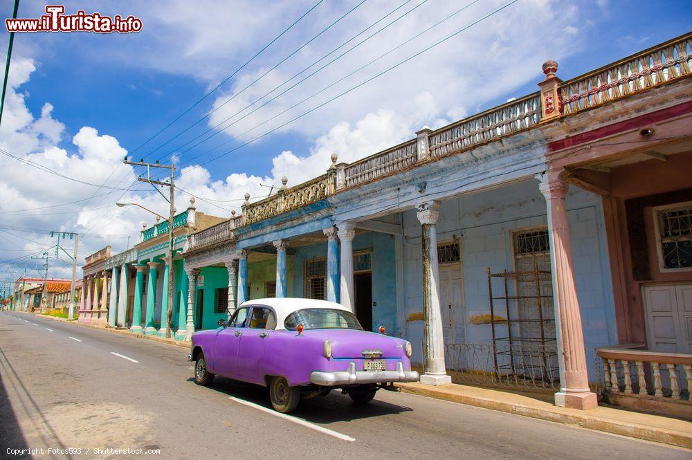 Immagine Una scena tipicamente cubana: una vecchia auto americana degli anni '50 passa davanti a case coloniali colorate e un po' malmesse a Pinar del Rio - © Fotos593 / Shutterstock.com