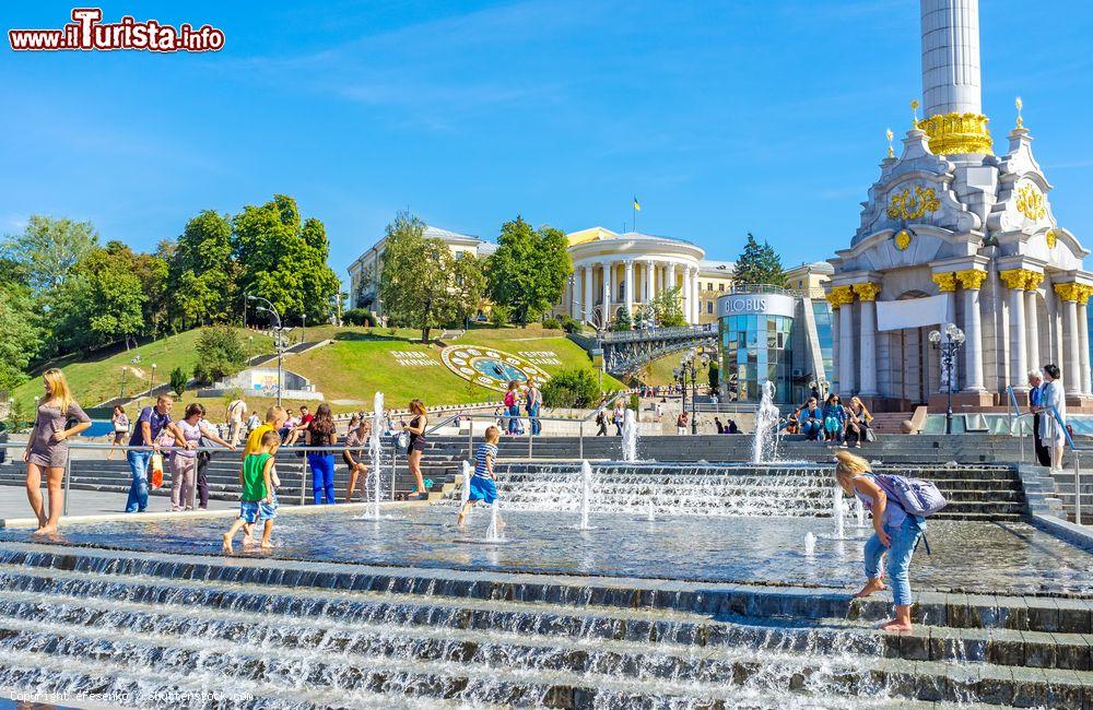 Immagine Bambini giocano nella fontana di Maidan Nezalezhnosti a Kiev, Ucraina. Independence Square ospita questa bella fontana con l'orologio di fiori e il palazzo Ottobre sullo sfondo - © eFesenko / Shutterstock.com