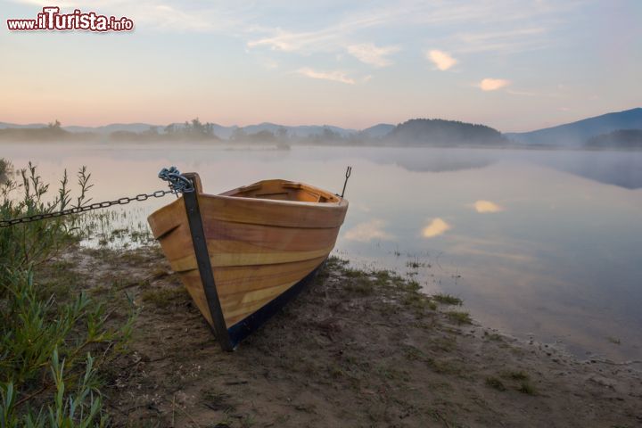 Immagine Barca sulla riva del Lago di Cerknica, Slovenia - Le luci del tramonto si riflettono sullo specchio d'acqua più famoso della Slovenia. Sulle sue sponde vengono ormeggiate imbarcazioni in legno come quella fotografata in questa immagine © FotoIvanKebe / Shutterstock.com