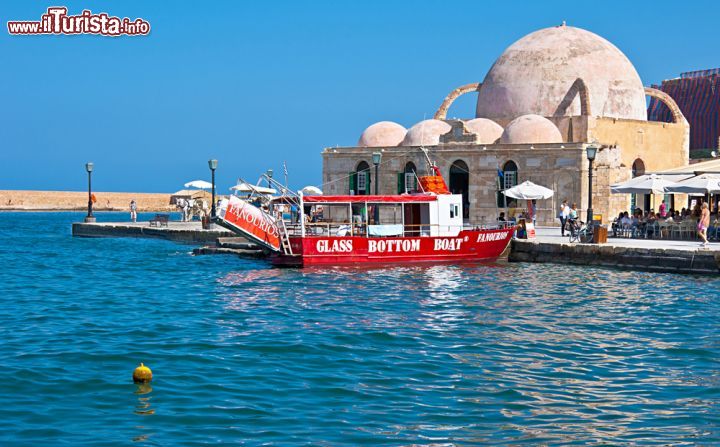 Immagine Una barca turistica rossa davanti alla moschea Hasan Pasha in attesa della partenza, Chania, Creta - © eFesenko / Shutterstock.com
