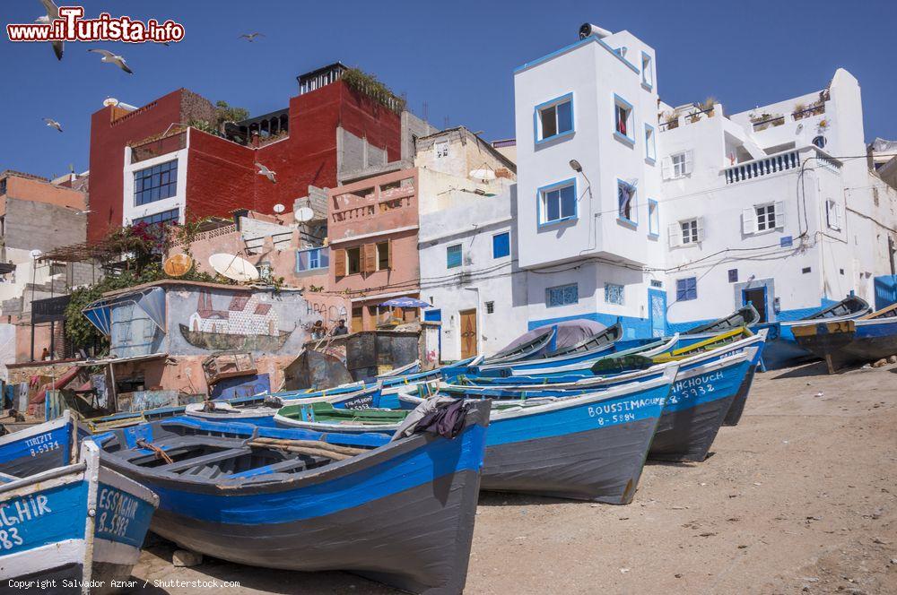 Immagine Barche da pesca sulla spiaggia del villaggio di Taghazout, Marocco. Sullo sfondo le case di questo centro del sud ovest del paese che dista poco più di 15 chilometri da Agadir - © Salvador Aznar / Shutterstock.com