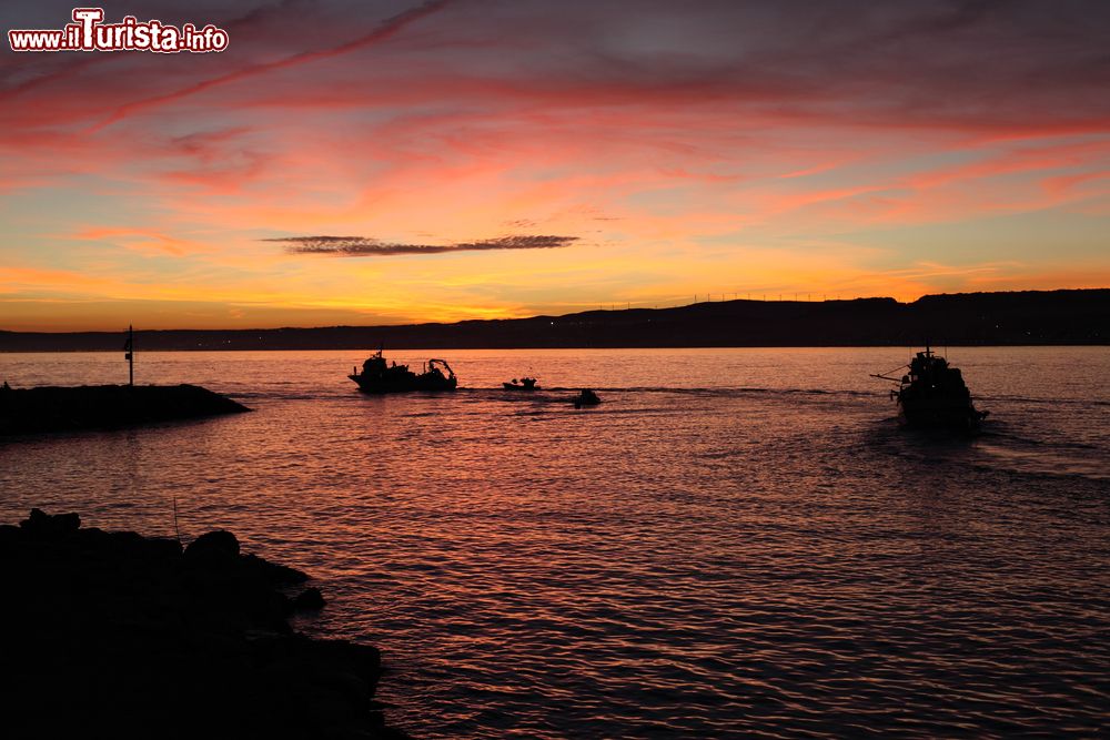 Immagine Barche lasciano il porto di Estepona per la pesca notturna, Spagna. A fare da cornice un meraviglioso tramonto con i colori del cielo riflessi sull'acqua del Mediterraneo.