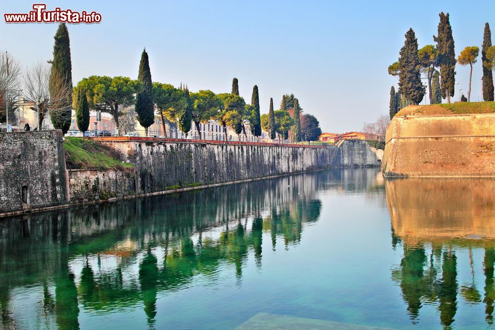 Immagine Una bella immagine del canale di Peschiera del Garda con cipressi e alberi, Veneto.