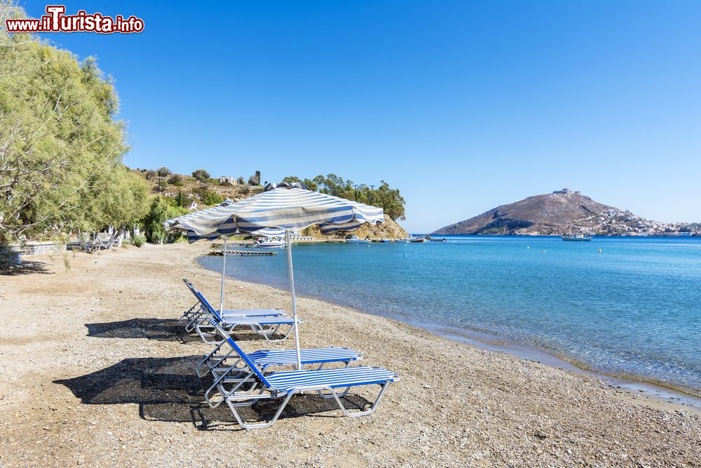 Immagine Una bella veduta del litorale dell'isola di Lero, Grecia. Sdraio e ombrellone sulla spiaggia ghiaiosa.