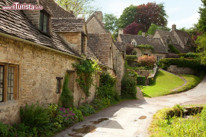 Immagine Case in pietra tra le colline dei Cotswolds a Bibury, Inghilterra - Un tratto di strada che si inerpica nel villaggio di Bibury e su cui si affacciano le tradizionali case rurali in pietra e mattoni a vista © Nella / Shutterstock.com