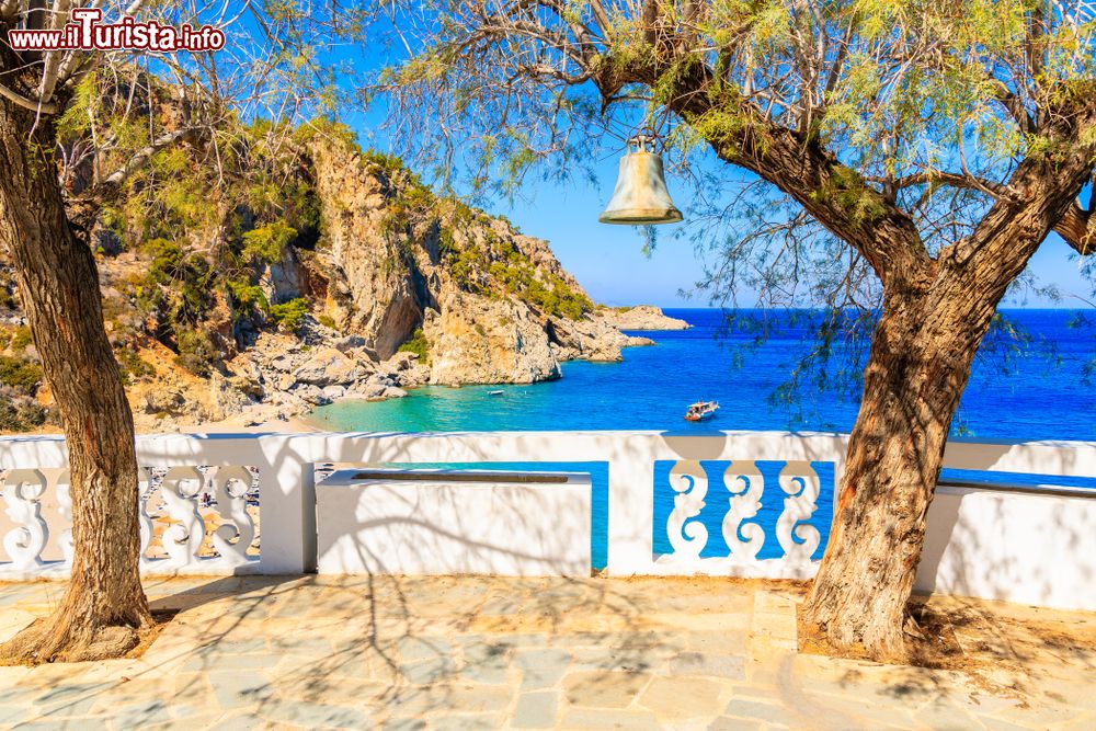 Immagine Una campana appesa su un albero nella spiaggia di Kyra Pynagia, isola Karpathos (Dodecaneso). Siamo in una piccola insenatura con spiaggia fra le rocce.