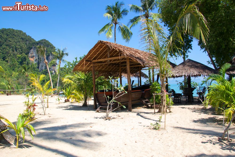 Immagine Capanne in paglia con tavolini e barche al riparo, isole di Koh Yao, Thailandia (Asia).