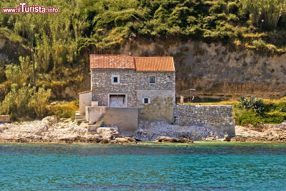 Immagine Una vecchia casa di pietra sulla costa dell'isola di Susak, in Croazia. A Susak si arriva con la linea di battello da Lussinpiccolo o con la linea di catamarano partente da Fiume; sull’isola non esistono strade ma soltanto sentieri di sabbia, percorribili a piedi, con la carriola o a bordo di trattori adibiti al trasporto di turisti.